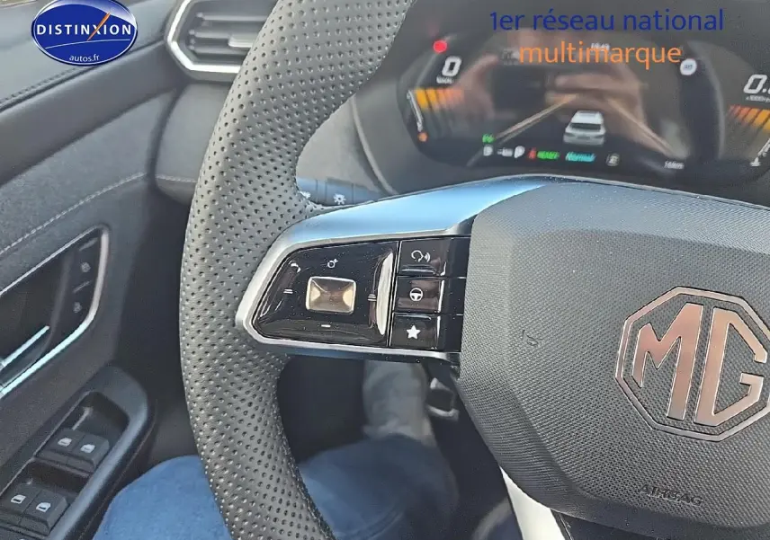 Vue rapprochée du volant perforé noir de la MG ZS Hybrid 197 avec commandes intégrées et tableau de bord numérique.