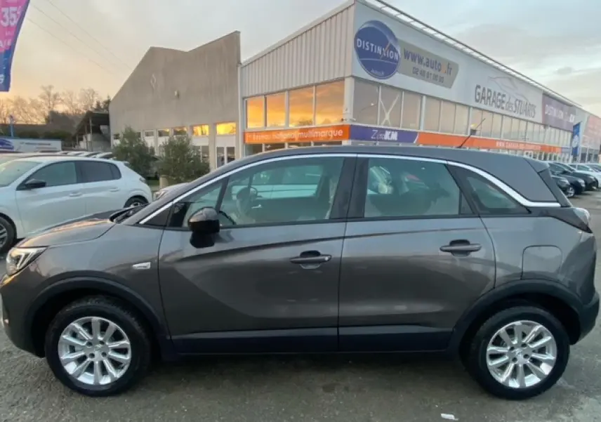 Vue de profil côté gauche d'un Opel Crossland gris magnetic 2022 avec jantes alliage 16 pouces et vitres surteintées.