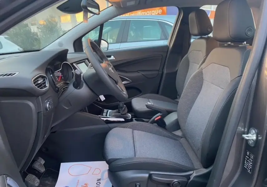 Vue intérieure côté conducteur de l’Opel Crossland gris Magnetic 2022, sièges tissu bicolore et volant multifonction.