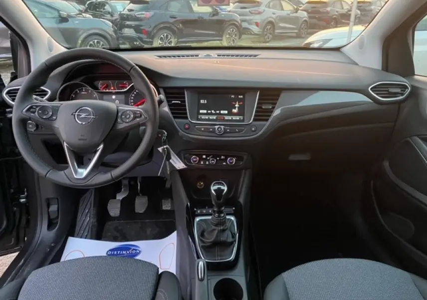 Vue intérieure avant de l'Opel Crossland gris Magnetic 2022, avec volant multifonction et boîte manuelle au premier plan.