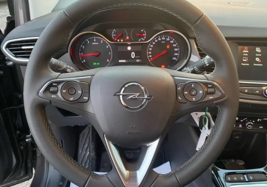 Vue rapprochée du volant noir de l’Opel Crossland 2022 avec tableau de bord et écran tactile en arrière-plan.