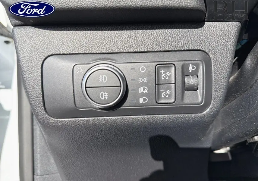 Gros plan sur le panneau de commande des phares et réglages lumineux du Ford Kuga blanc Glacier, côté gauche du tableau de bord.
