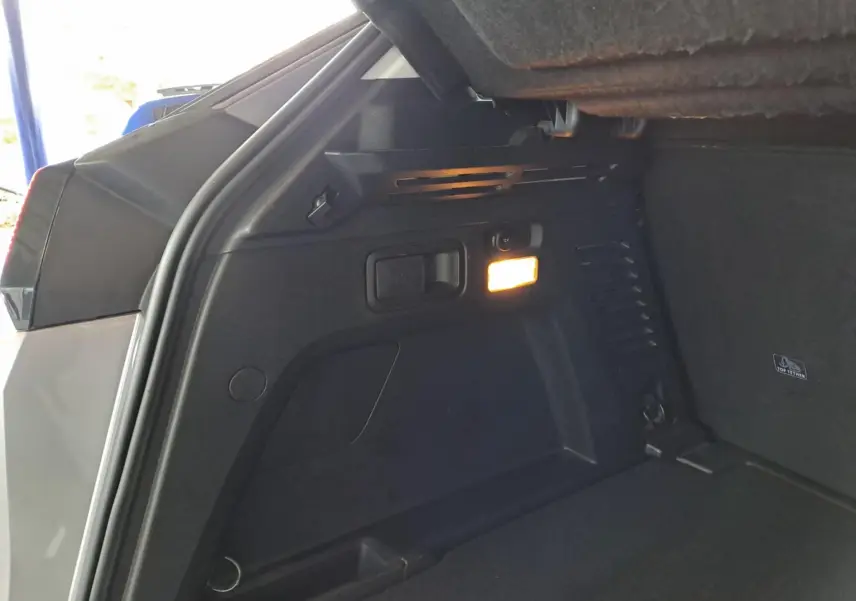 Vue intérieure du coffre du Peugeot 3008 gris Artense, mettant en valeur un éclairage latéral et des rangements intégrés.
