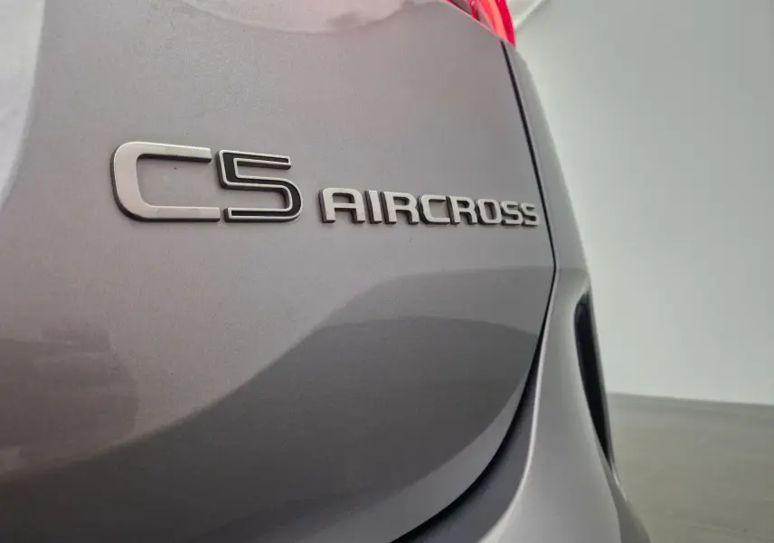 Gros plan sur l'arrière droit gris Artense d'un Citroën C5 Aircross 2024, mettant en valeur le logo du modèle.