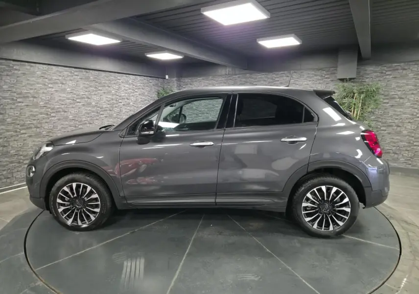Fiat 500X gris vue de profil côté gauche, avec jantes alliage 17 pouces et vitres surteintées.