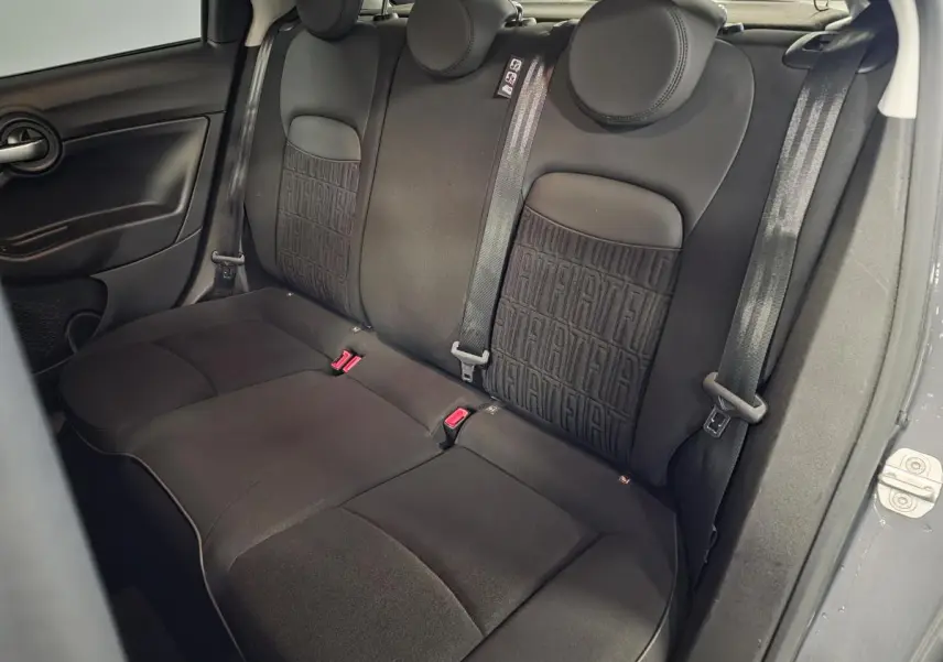 Vue intérieure sur la banquette arrière noire de la Fiat 500X 2024 avec monogramme FIAT sur les dossiers.