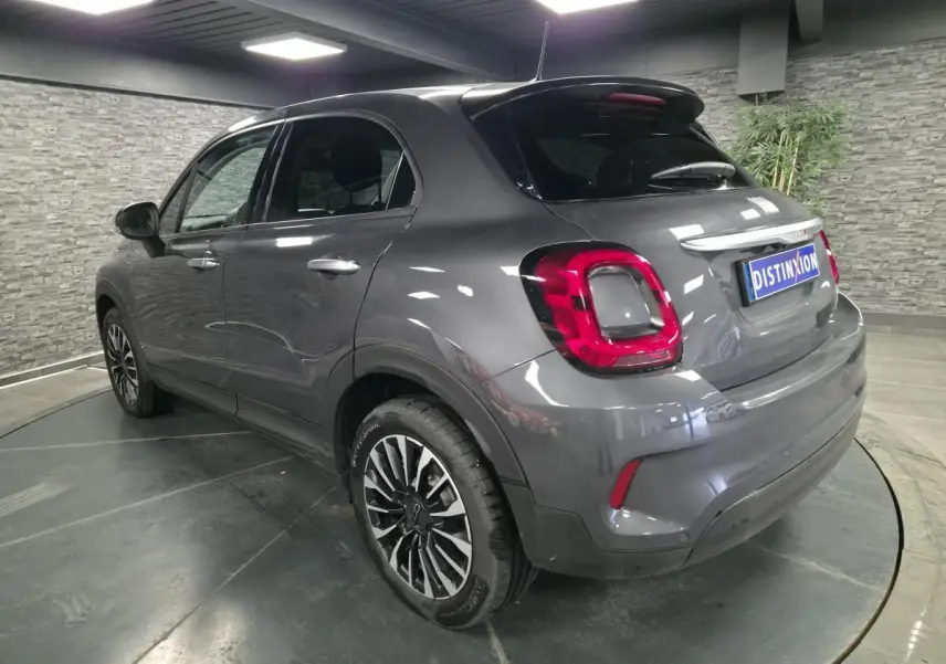 Fiat 500X gris métallisé vue 3/4 arrière droit, avec jantes alliage 17 pouces et feux arrière LED distinctifs.