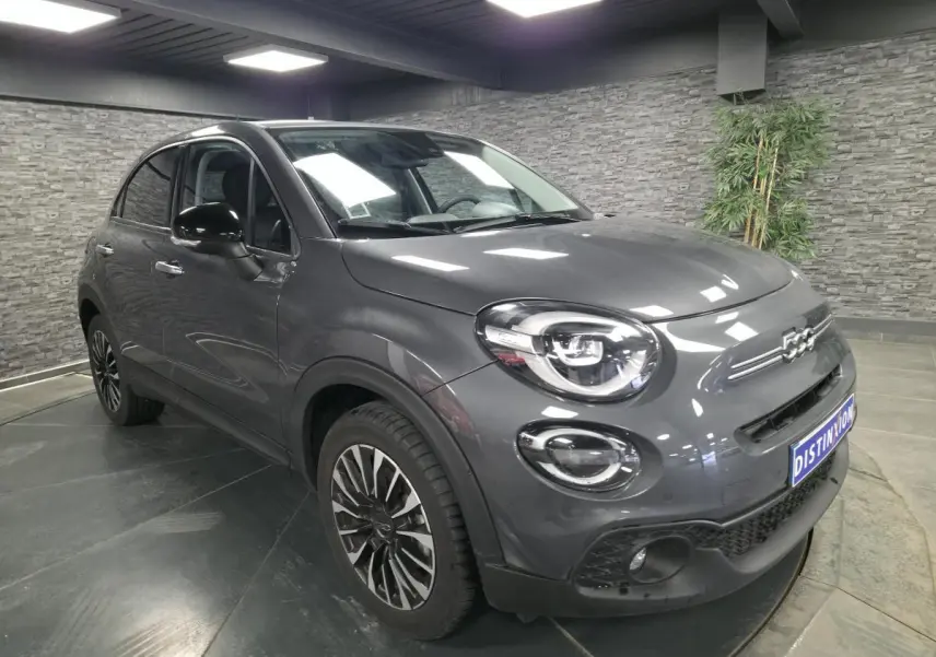 Fiat 500X gris métallisé vue 3/4 avant droit, avec jantes alliage 17 pouces et projecteurs LED distinctifs.