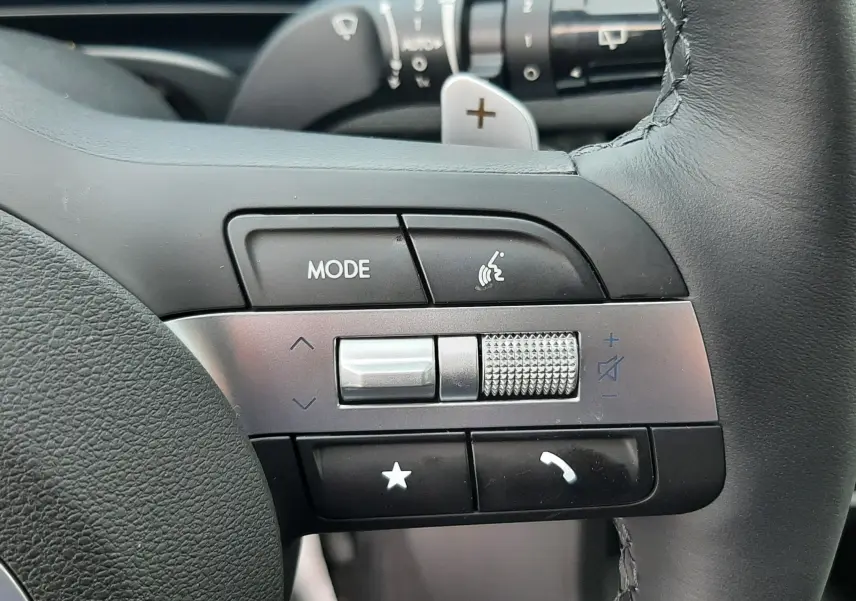 Gros plan sur les commandes multifonctions à gauche du volant du Hyundai Tucson 2025, avec molette de volume et boutons tactiles.