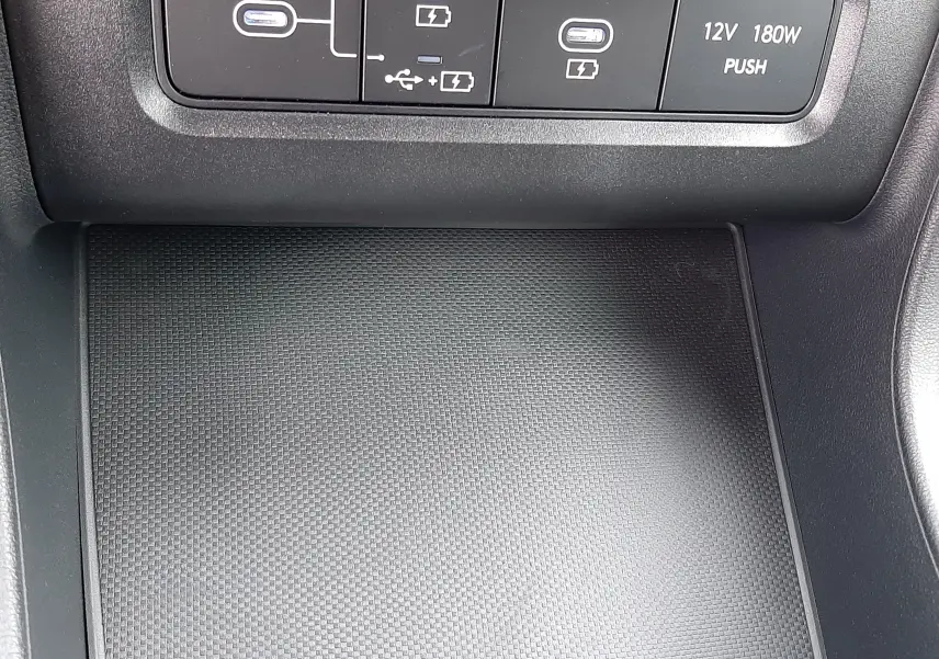 Détail de la console centrale du Hyundai Tucson 2025 avec prises USB, charge sans fil et prise 12V, finition noire.
