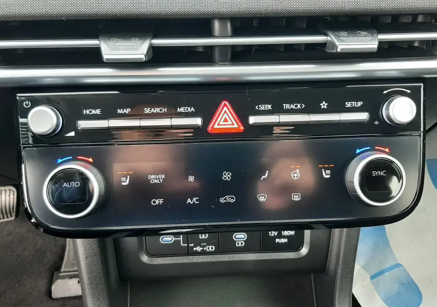 Vue rapprochée de la console centrale du Hyundai Tucson 2025 en gris Ecotronic, avec commandes climatisation et multimédia.