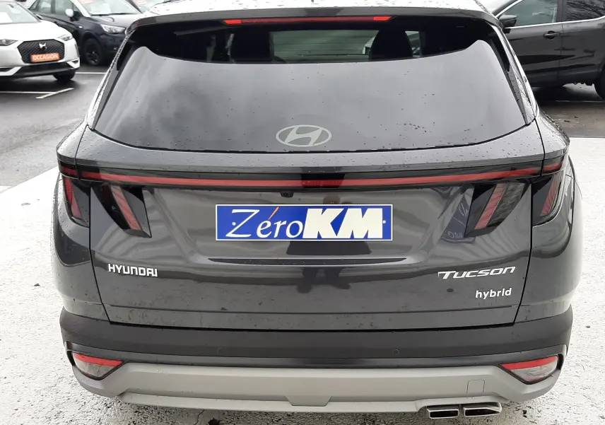 Vue arrière d'un Hyundai Tucson hybride gris Ecotronic avec hayon électrique et double sortie d'échappement visible.