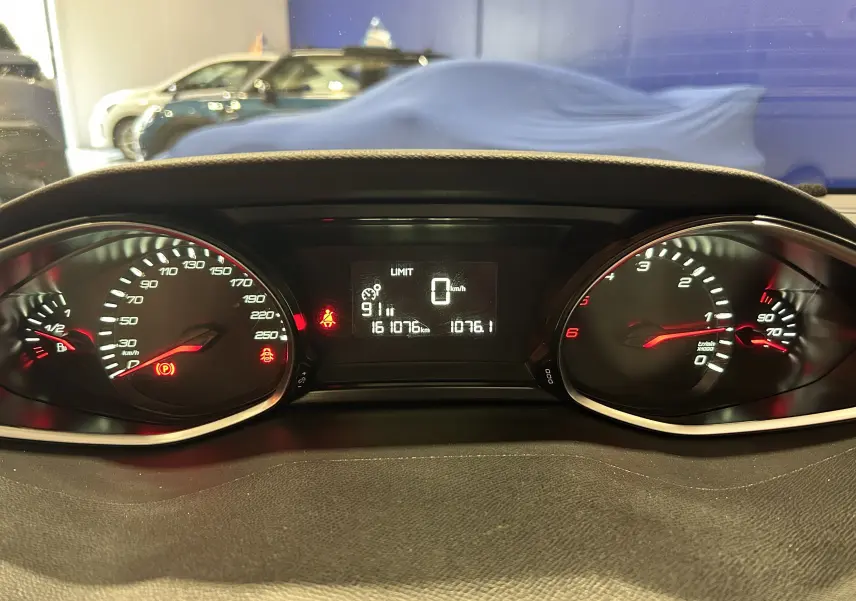 Vue rapprochée du tableau de bord noir de la Peugeot 308 SW avec affichage digital et compteurs analogiques éclairés.