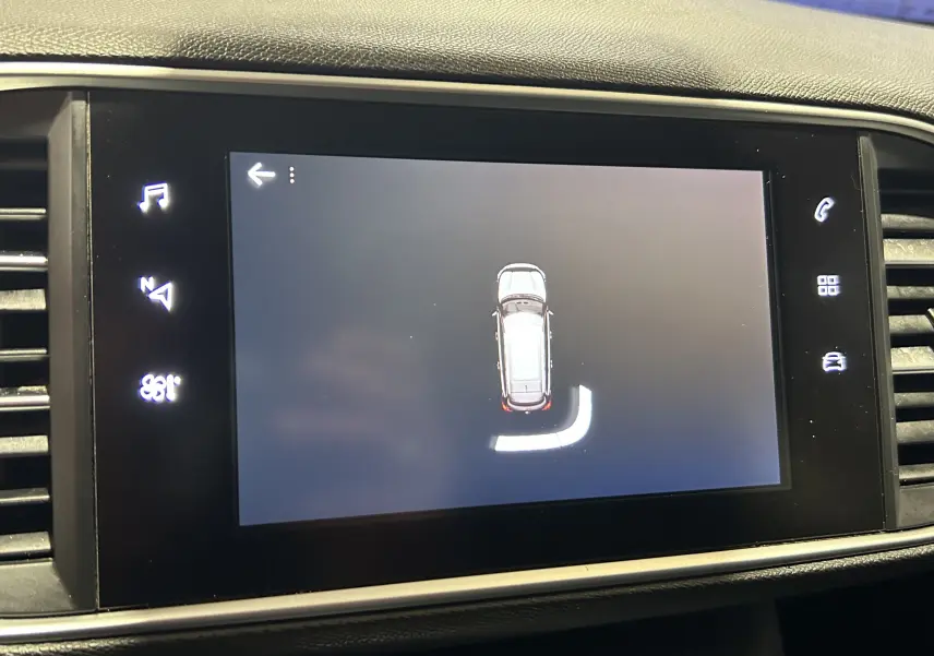 Écran tactile du tableau de bord de la Peugeot 308 SW noir, affichant la vue de dessus du véhicule en marche arrière.