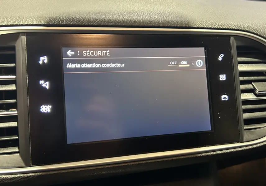 Écran tactile central de la Peugeot 308 SW noir affichant le menu sécurité avec l'alerte attention conducteur activée.