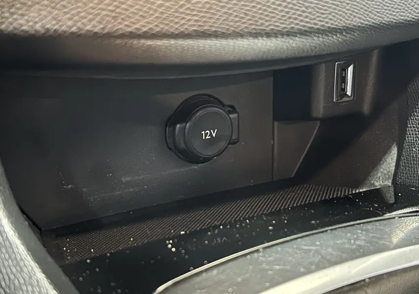 Prise 12V et port USB dans l'espace de rangement intérieur d'une Peugeot 308 SW noire, vue rapprochée.
