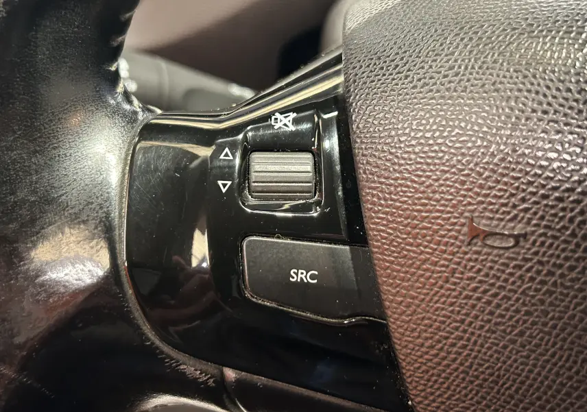 Gros plan sur les commandes audio noires intégrées au volant en cuir marron du Peugeot 308 SW 2018.