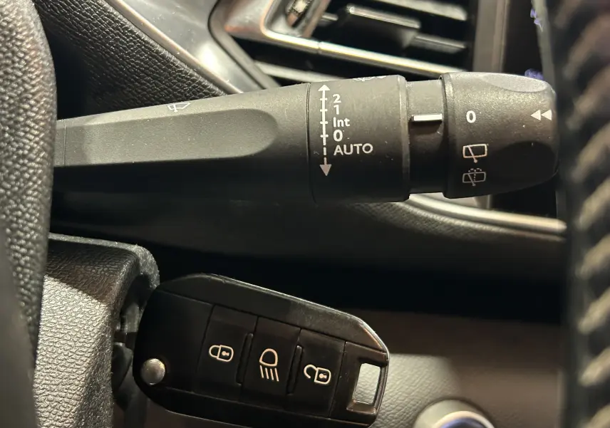 Gros plan sur la commande d’essuie-glace et la clé noire dans l’habitacle d’une Peugeot 308 SW noire de 2018.
