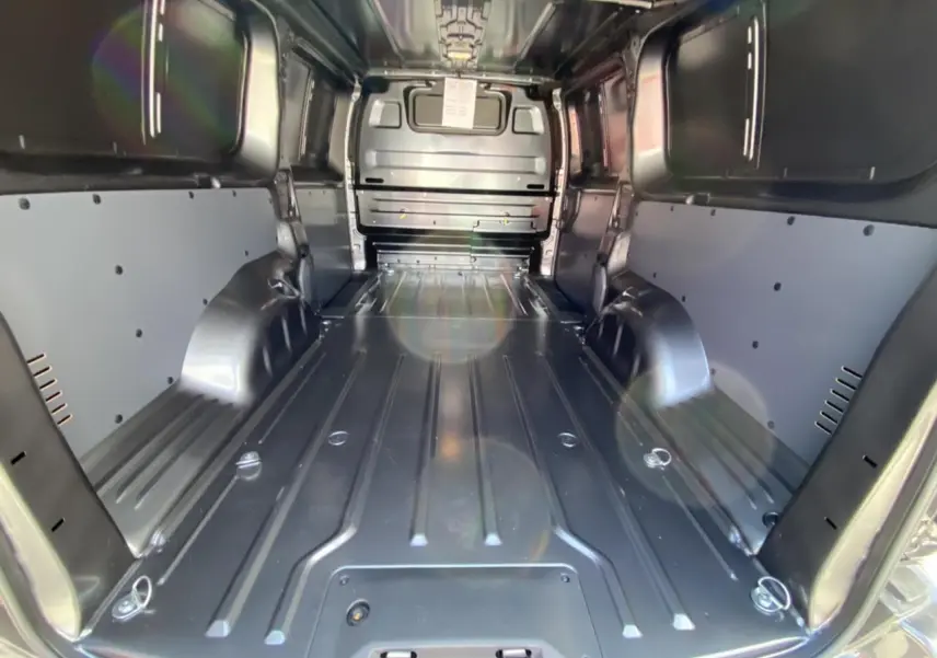 Vue intérieure arrière du Peugeot Expert Fourgon gris platinium, montrant l'espace de chargement tôlé et les parois latérales renforcées.