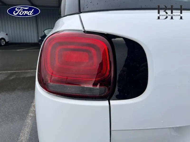 Gros plan sur le feu arrière gauche rouge d'une Citroën C3 Aircross blanche, avec contour noir brillant.