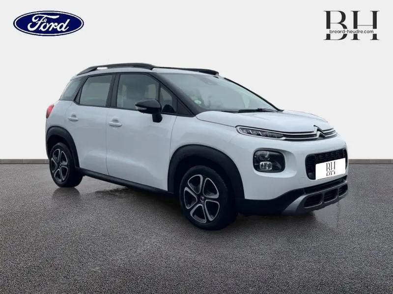 Citroën C3 Aircross blanc Natural White vue 3/4 avant droit avec barres de toit et jantes distinctives.