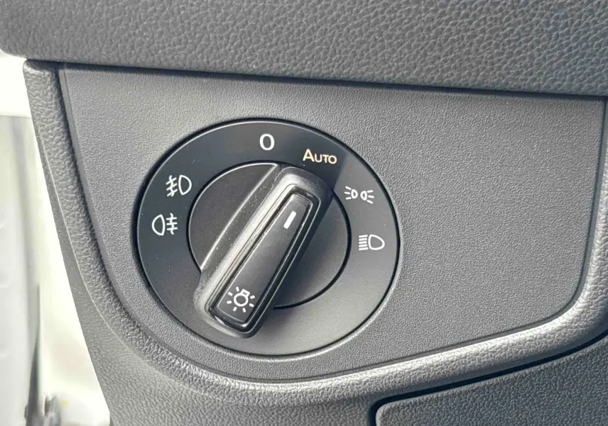 Gros plan sur le bouton de commande des phares dans l’habitacle du Volkswagen Taigo blanc, côté gauche.