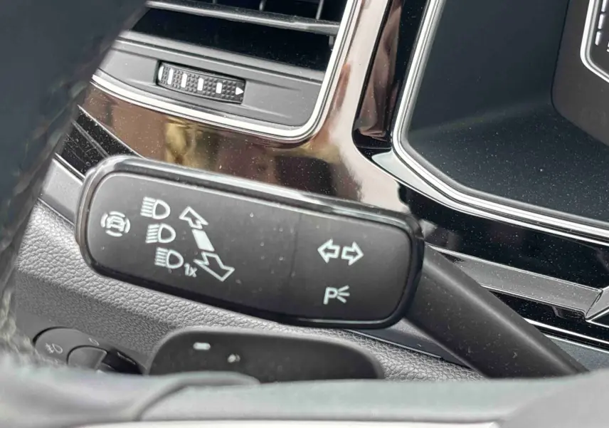 Gros plan sur la manette de clignotant et feux du Volkswagen Taigo 2025, intérieur noir avec détails chromés.