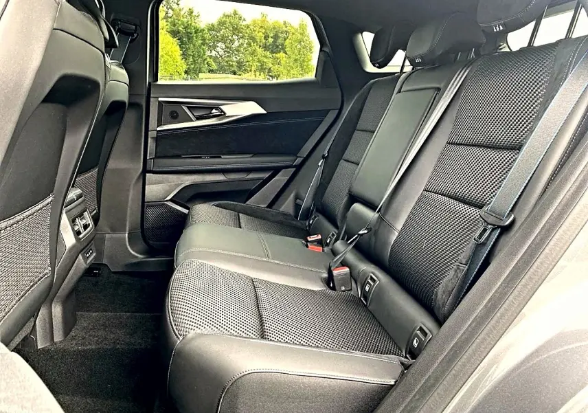 Vue latérale droite de la banquette arrière noire en tissu et alcantara du Renault Austral gris schiste, avec accoudoir central relevé.