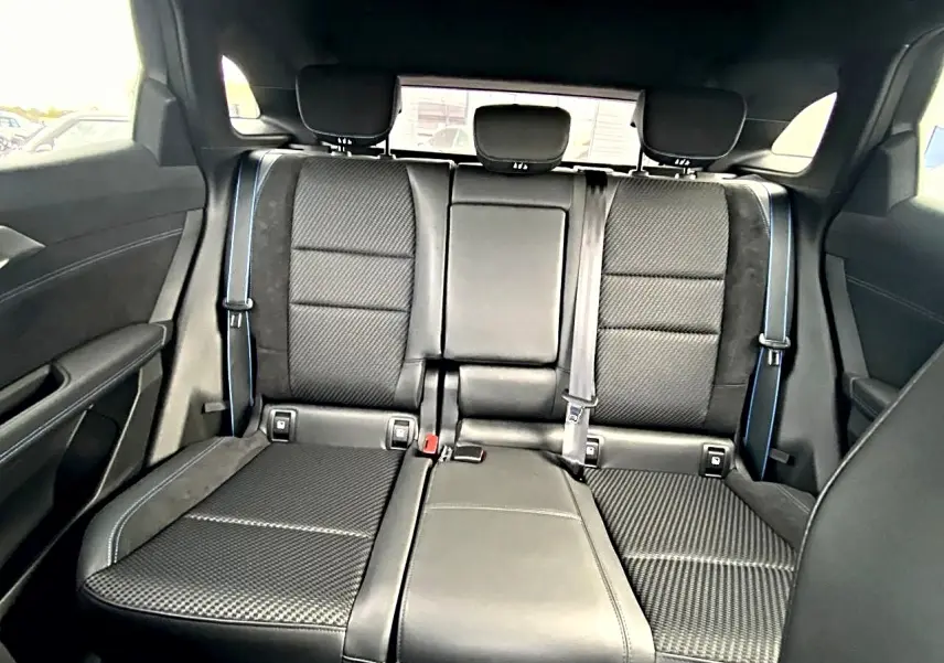 Vue arrière intérieure montrant la banquette noire en tissu carbone et alcantara avec surpiqûres bleues du Renault Austral 2026.