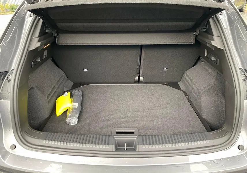 Coffre ouvert vu de l'arrière d'un Renault Austral gris schiste, avec tapis et accessoires de sécurité visibles.