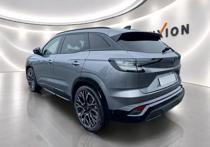 Vue 3/4 arrière droite du Renault Austral gris schiste avec jantes alu et toit noir brillant dans un showroom moderne.