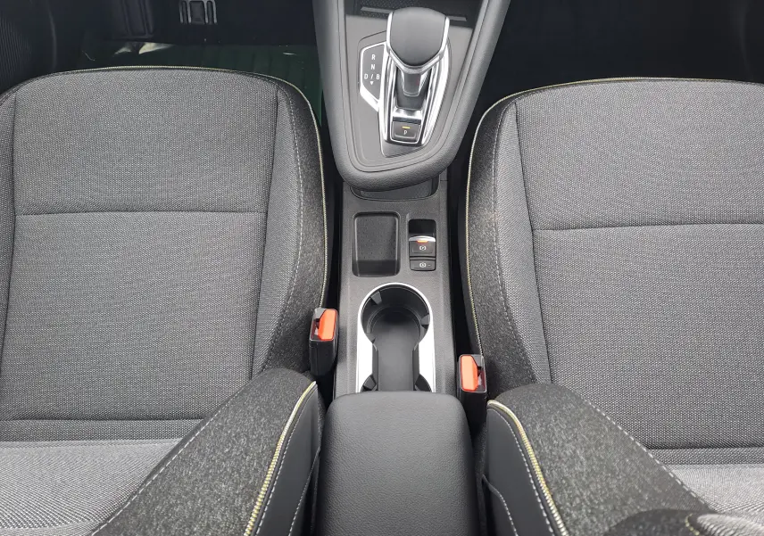 Vue plongeante sur la console centrale et les sièges en tissu gris avec surpiqûres jaunes de la Renault Symbioz 2025.