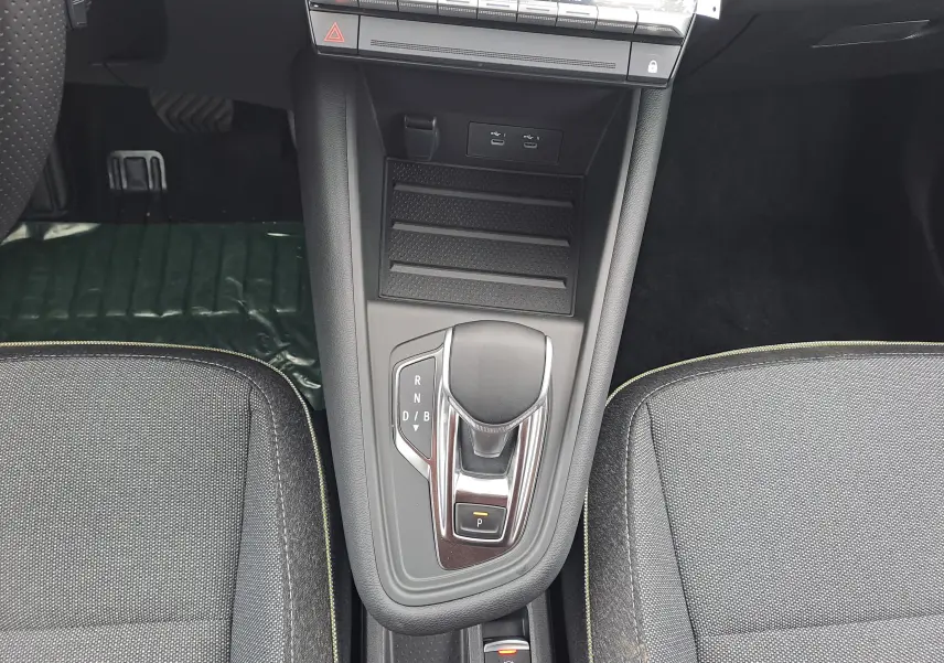 Vue plongeante sur la console centrale de la Renault Symbioz 2025, avec levier de boîte auto et sièges tissu gris.