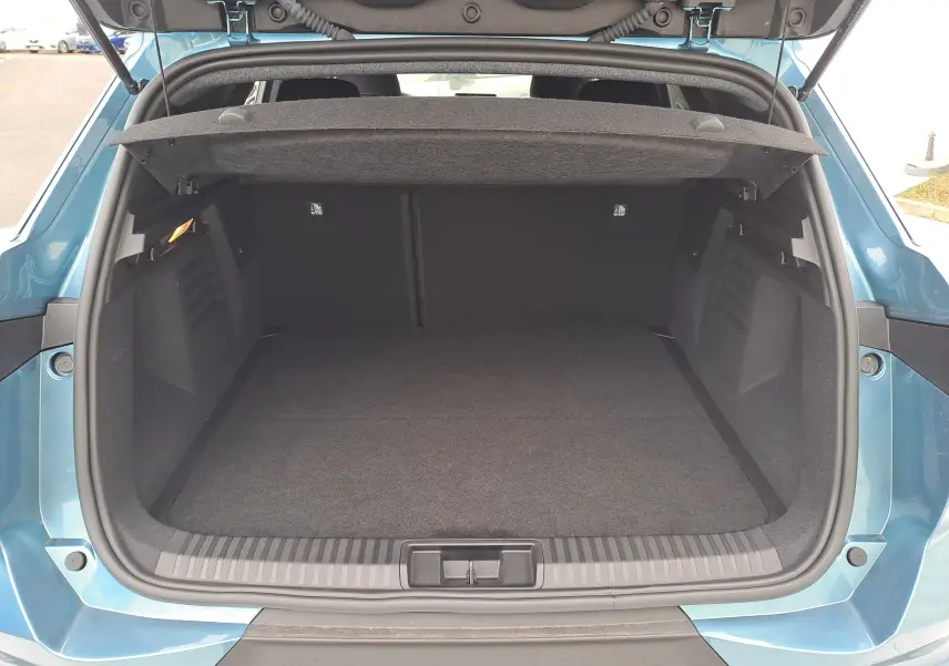 Coffre ouvert vu de l'arrière d'une Renault Symbioz bleu mercure, montrant un espace de chargement propre et spacieux.