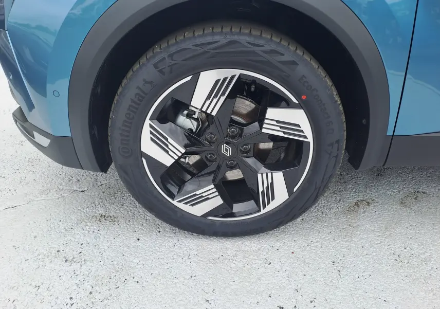 Gros plan sur la roue avant gauche du Renault Symbioz bleu mercure avec jante alliage noire et blanche design géométrique.