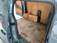 Vue intérieure côté droit du Renault Express Van gris 2021 montrant l'espace de chargement avec cloison vitrée et bois.