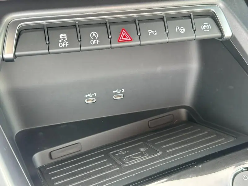 Gros plan sur la console centrale noire de l'Audi A3 Sportback 2024 avec boutons de sécurité et ports USB-C doubles.