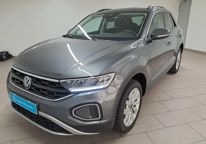 Volkswagen T-Roc gris Indium en 3/4 avant droit, avec jantes alliage 17'' Johannesburg et feux LED allumés.