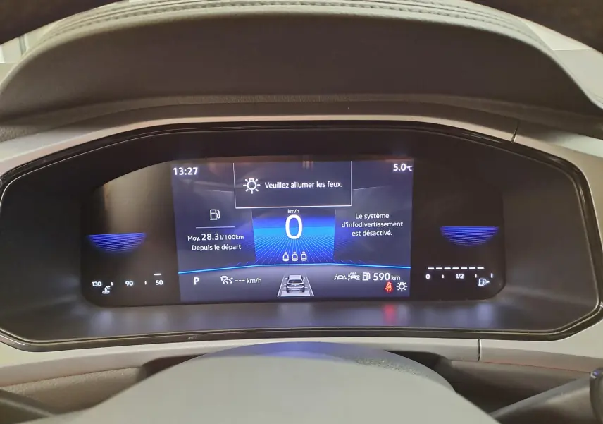 Affichage numérique du tableau de bord du Volkswagen T-Roc 1.5 TSI 150 DSG7 LIFE, indiquant vitesse zéro et alertes système.