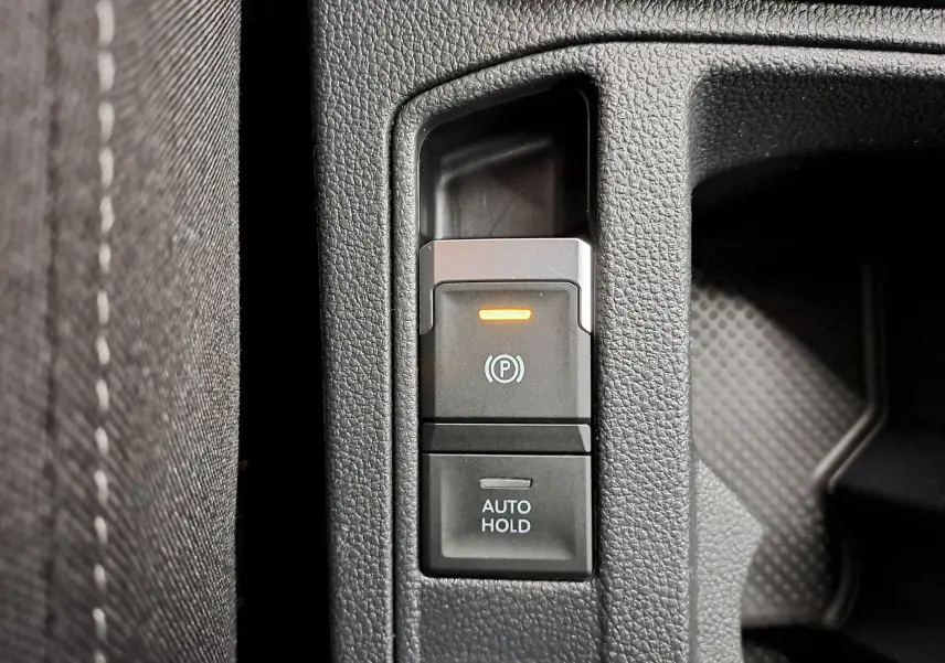 Gros plan sur la commande de frein à main électronique et fonction Auto Hold dans un Volkswagen T-Roc 2024.