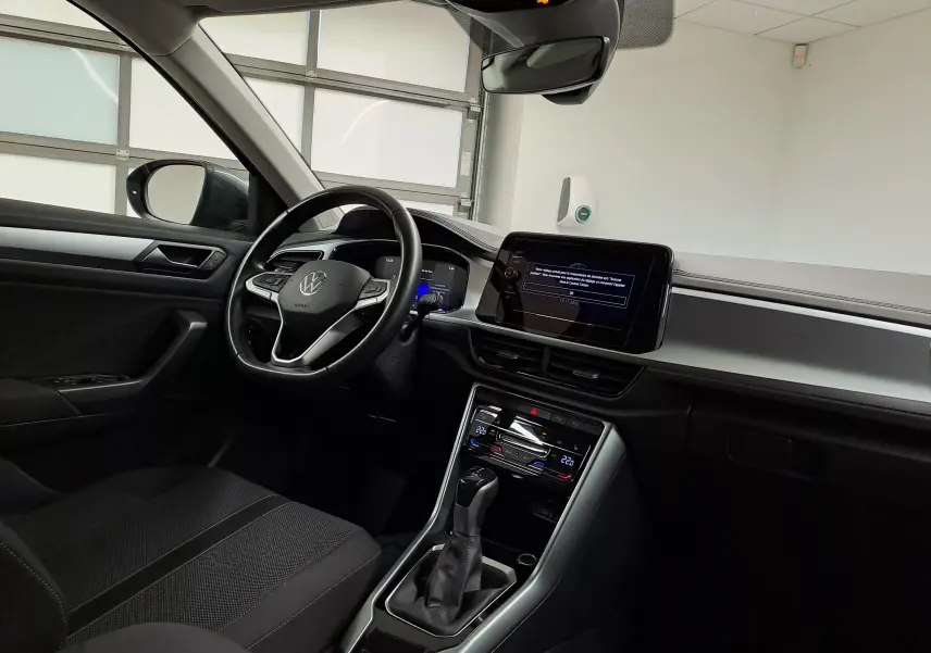 Vue intérieure côté conducteur du Volkswagen T-Roc 1.5 TSI 150 DSG7 LIFE avec tableau de bord moderne et écran tactile.