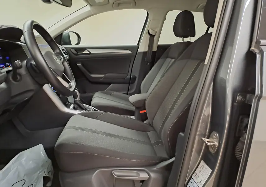 Vue intérieure côté gauche du Volkswagen T-Roc 2024 gris Indium, montrant les sièges avant et le volant.