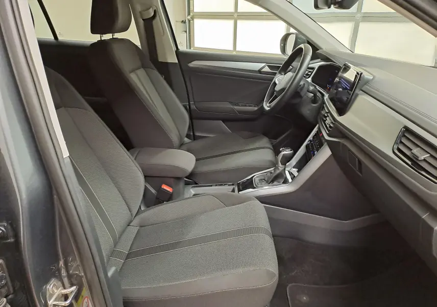 Intérieur avant droit du Volkswagen T-Roc 2024 gris Indium, montrant sièges tissu et tableau de bord moderne.