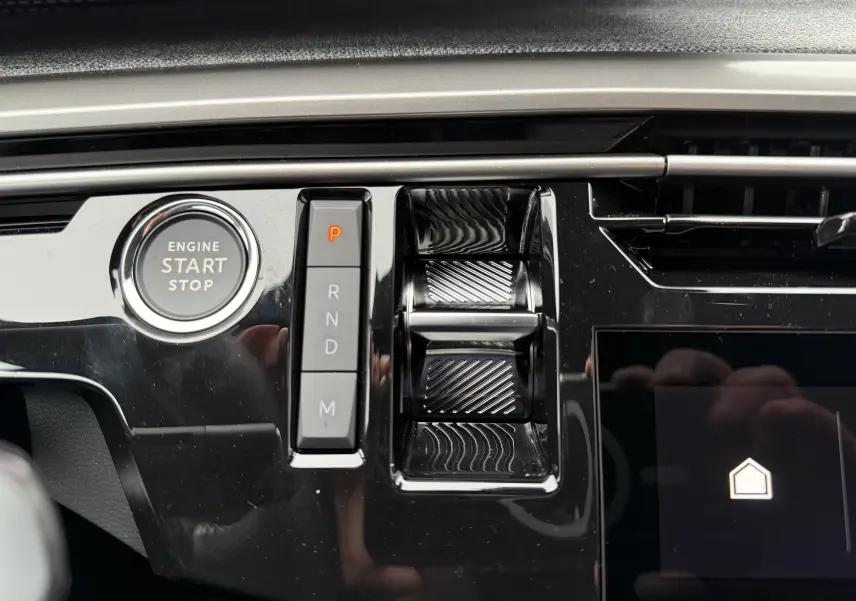 Gros plan sur la console centrale noire brillante du Peugeot 3008 Hybrid avec bouton start/stop et sélecteur de vitesses électronique.