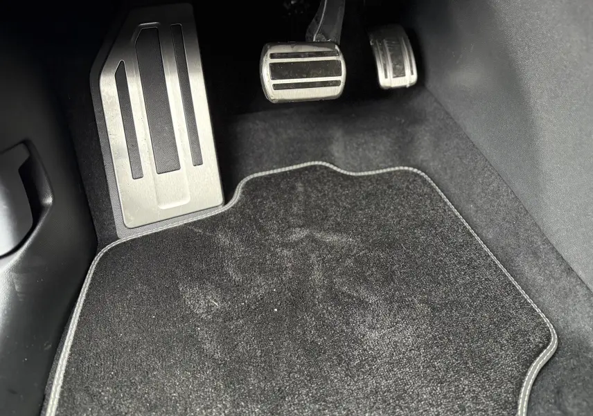 Vue rapprochée des pédales en métal brossé côté conducteur du Peugeot 3008 Hybrid 2025 avec tapis noir.