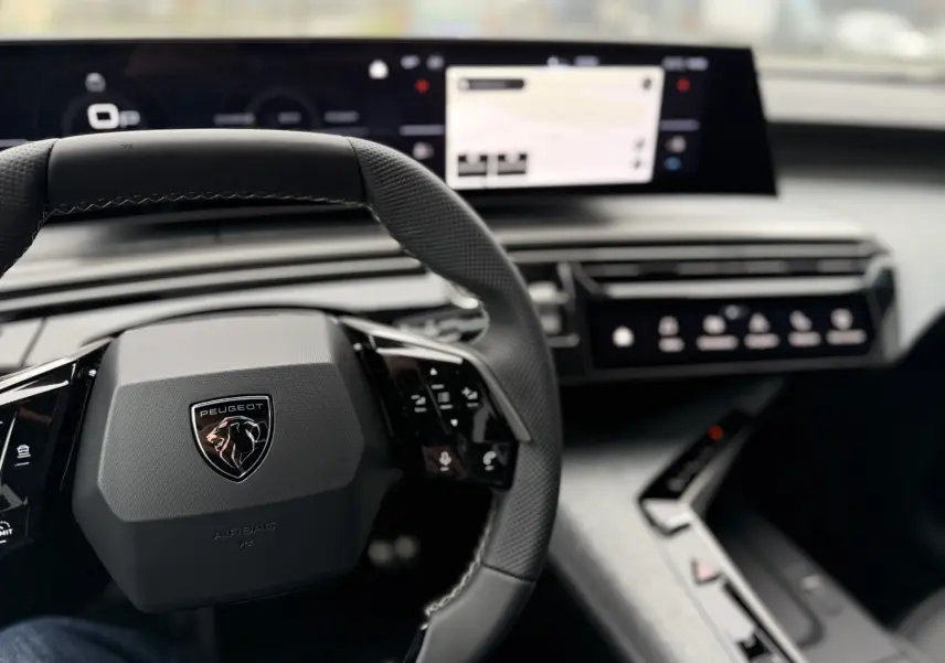 Vue rapprochée du volant et tableau de bord numérique du Peugeot 3008 Hybrid 2025, ambiance intérieure moderne et épurée.