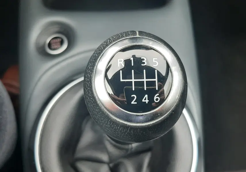 Gros plan sur le levier de vitesse manuel noir et chrome du Nissan Juke gris, montrant les six rapports et la marche arrière.