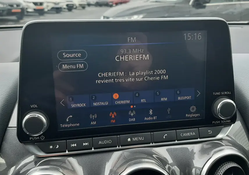 Vue intérieure centrée sur l'écran multimédia du Nissan Juke gris 2020, affichant la radio FM Cherie FM.