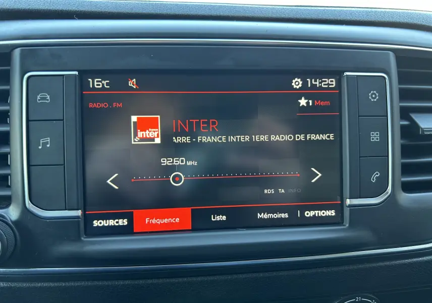 Gros plan sur l'écran tactile central du tableau de bord du Citroën Jumpy blanc, affichant la radio FM sur France Inter.