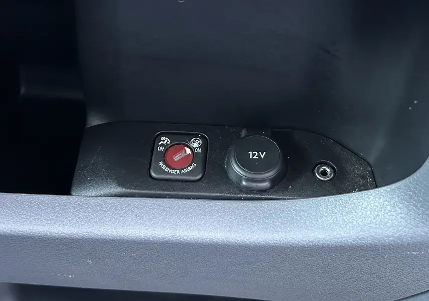 Détail intérieur montrant l'interrupteur airbag passager et prise 12V sur une surface noire du Citroën Jumpy blanc.
